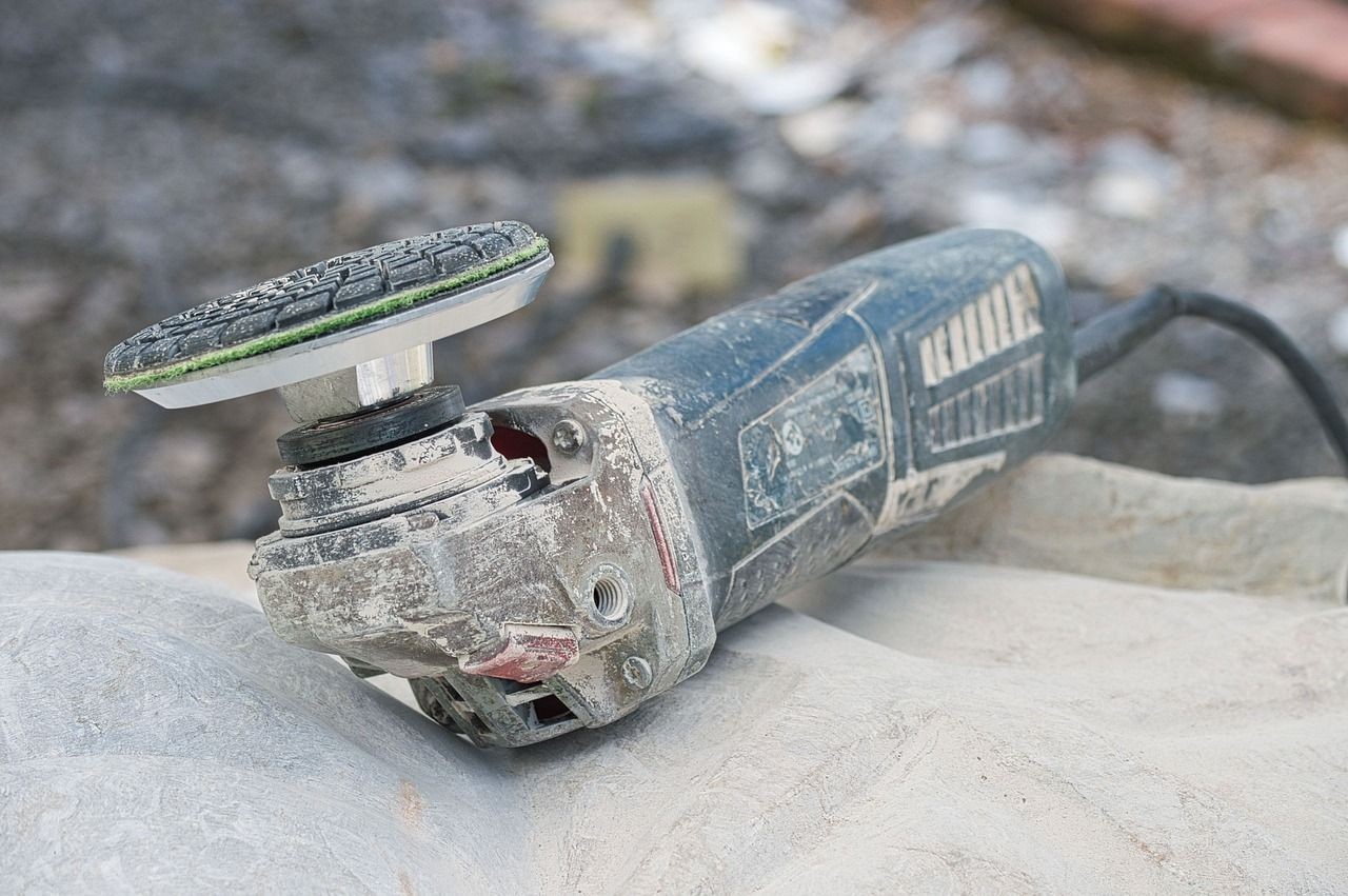 Close-up of an angle grinder placed on a stone surface, used for sanding or grinding.